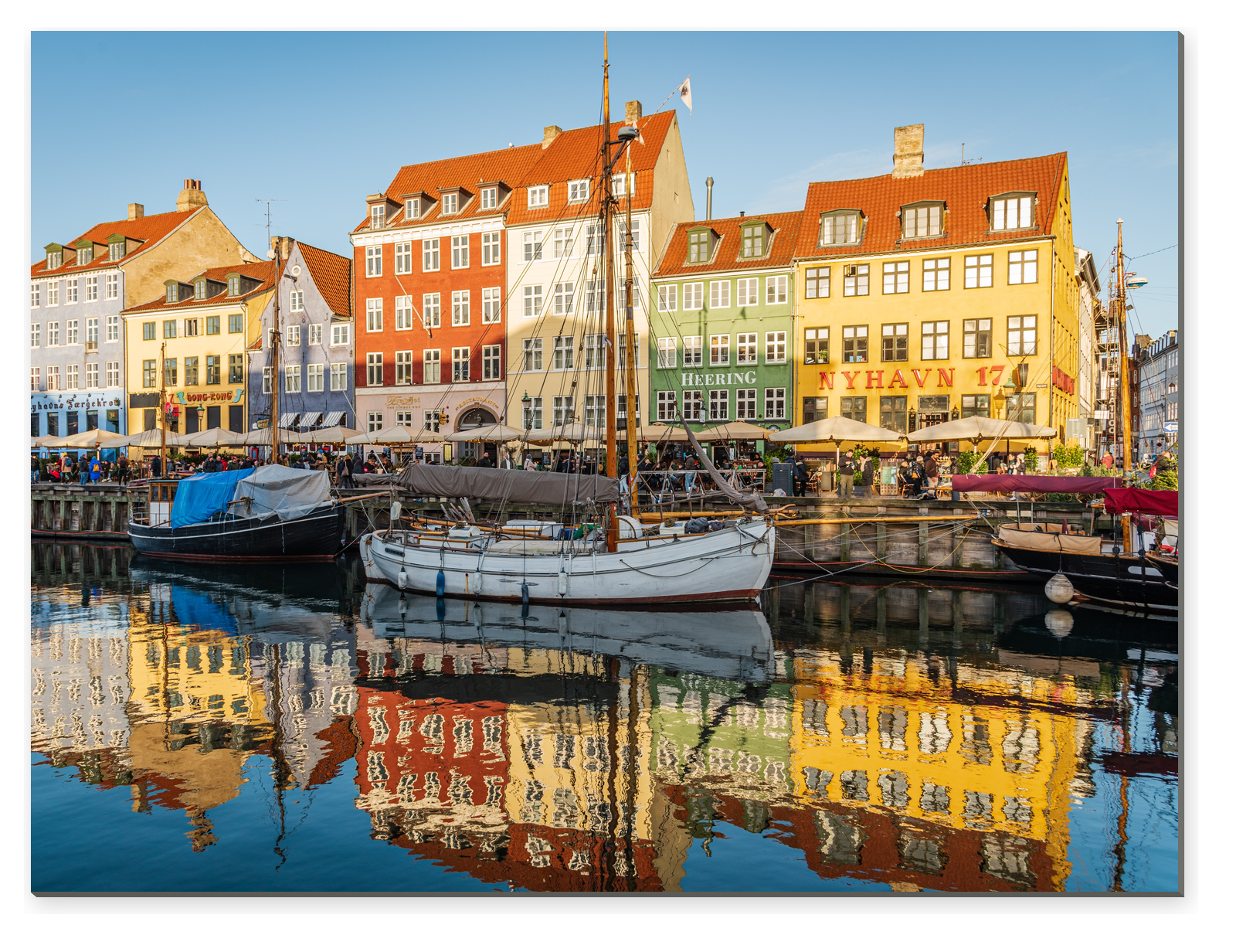 Barevné historické domy a plachetnice v přístavu Nyhavn v Kodani s odrazy ve vodě