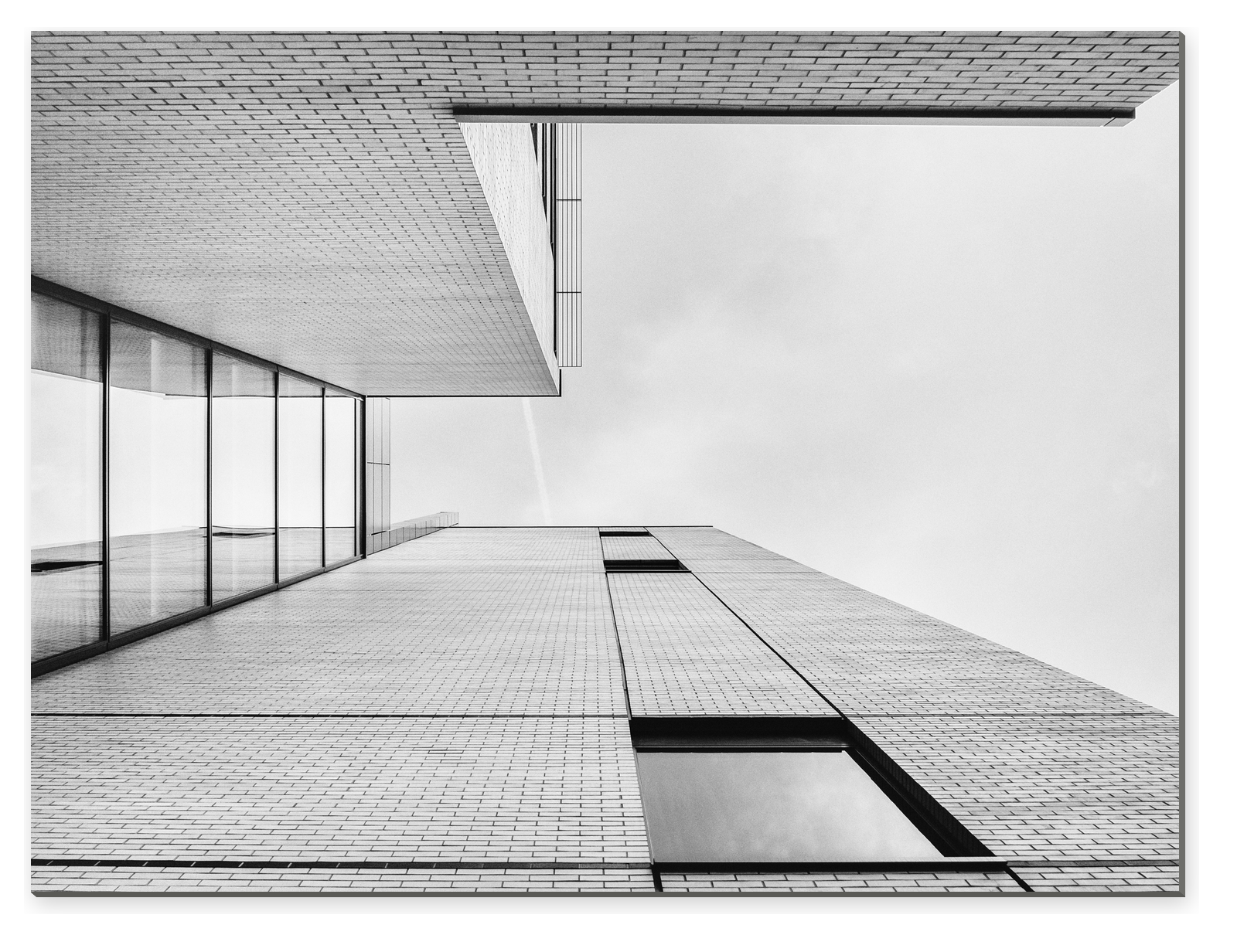 Černobílý pohled vzhůru na fasádu moderní budovy s okny a geometrickými liniemi